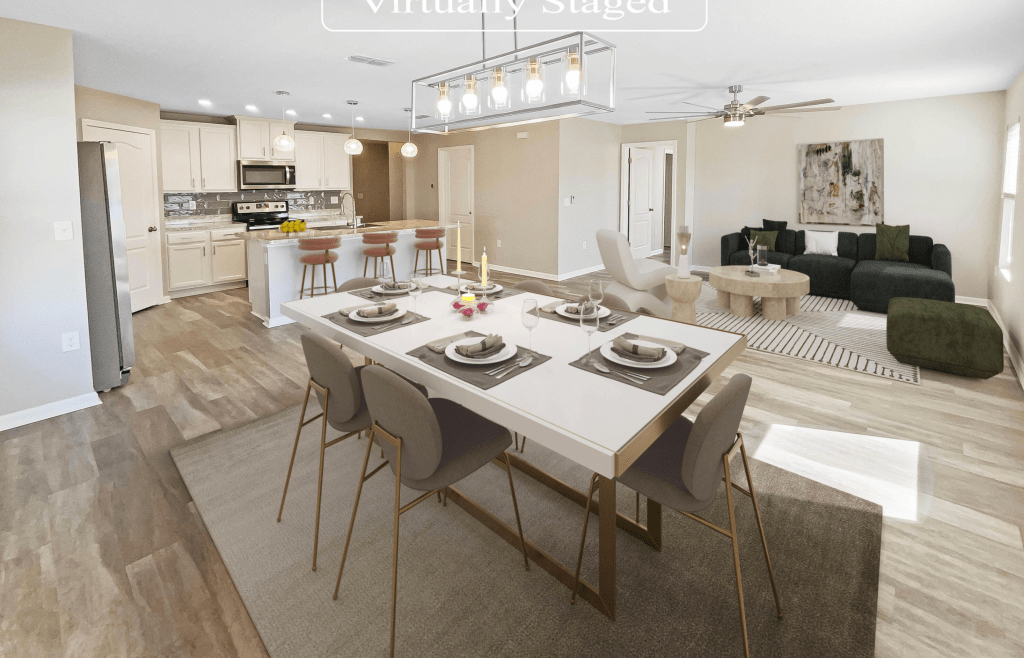 A modern, virtually staged dining area with a white table set for four, featuring stylish chairs and a decorative centerpiece. In the background, a contemporary kitchen with stainless steel appliances and light cabinetry, along with a cozy living room area featuring a green sofa and a circular coffee table.
